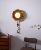 Angled and lit, this close crop of the Clérachic sconce takes in the dresser edge, a cup and a chair alongside.