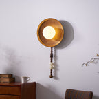 Mounted above a wooden dresser, the lit Clérachic sconce casts a warm glow through a faint haze in the bedroom.