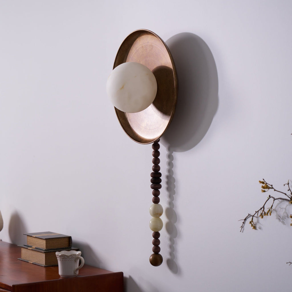 Seen at an angle with the light off, the round shade sits proud of the brass-tone tray on this Clérachic sconce.
