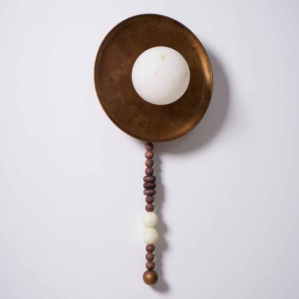 Photographed again on white, the Clérachic sconce shows its full shade and the wood and marble bead strand.