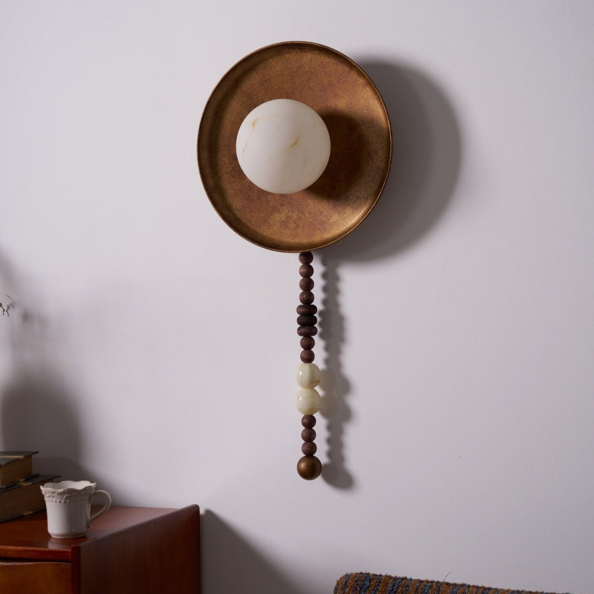 In this tight, unlit close-up, the Clérachic sconce's pale disc and beaded drop show without the bulb glowing.