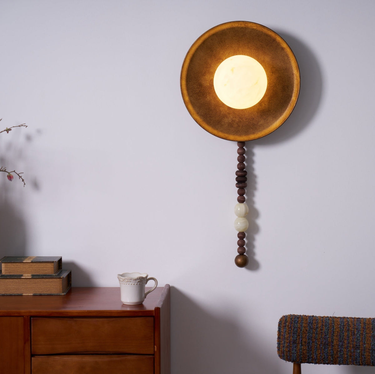 Cropped closer and angled upward, this shot enlarges the glowing shade of the Clérachic sconce above the dresser.