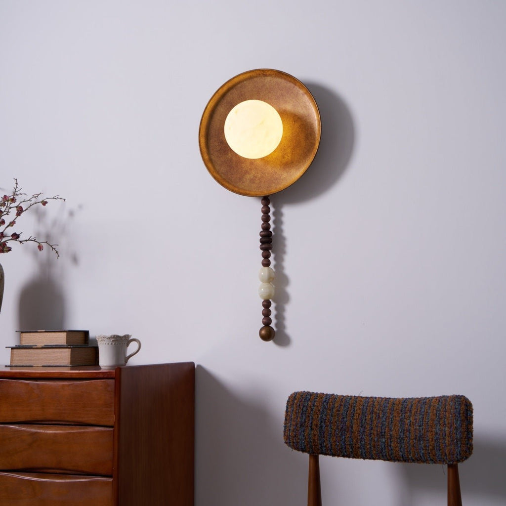 From a slightly different angle, the lit Clérachic sconce hangs above the same dresser and a bare branch.