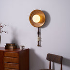 A closer angle shows the Clérachic sconce's bead drop hanging past a dresser topped with books and a cup.