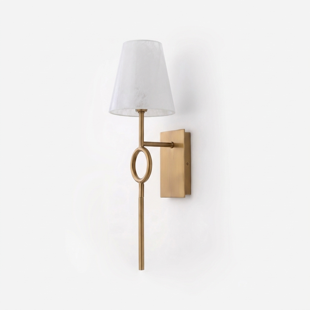 Angled on a plain backdrop, the brushed brass rod and oval ring of this Clérachic wall sconce rise beneath its alabaster cone shade.