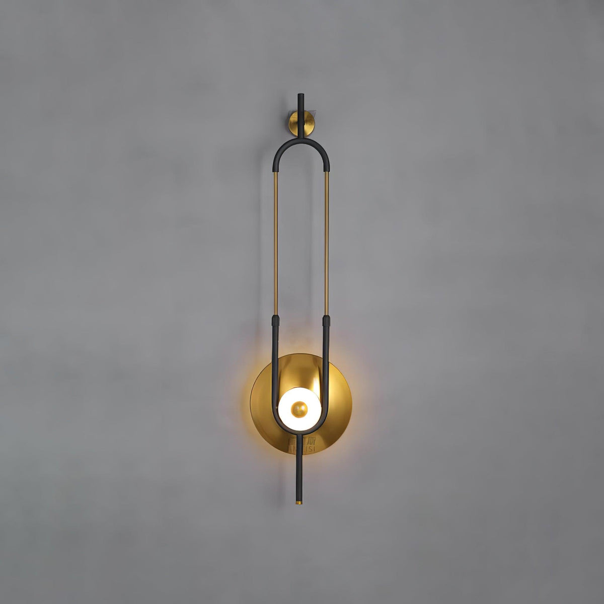This Clérachic wall sconce is photographed against a plain grey wall, showing the full loop from wall bracket to lit base.