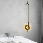 A Clérachic wall sconce glows beside a bed dressed in white linen and a grey knit cushion.