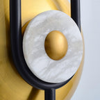 Close-up of the Clérachic wall sconce's white marble ring wrapped in gold, with the black loop crossing behind it.