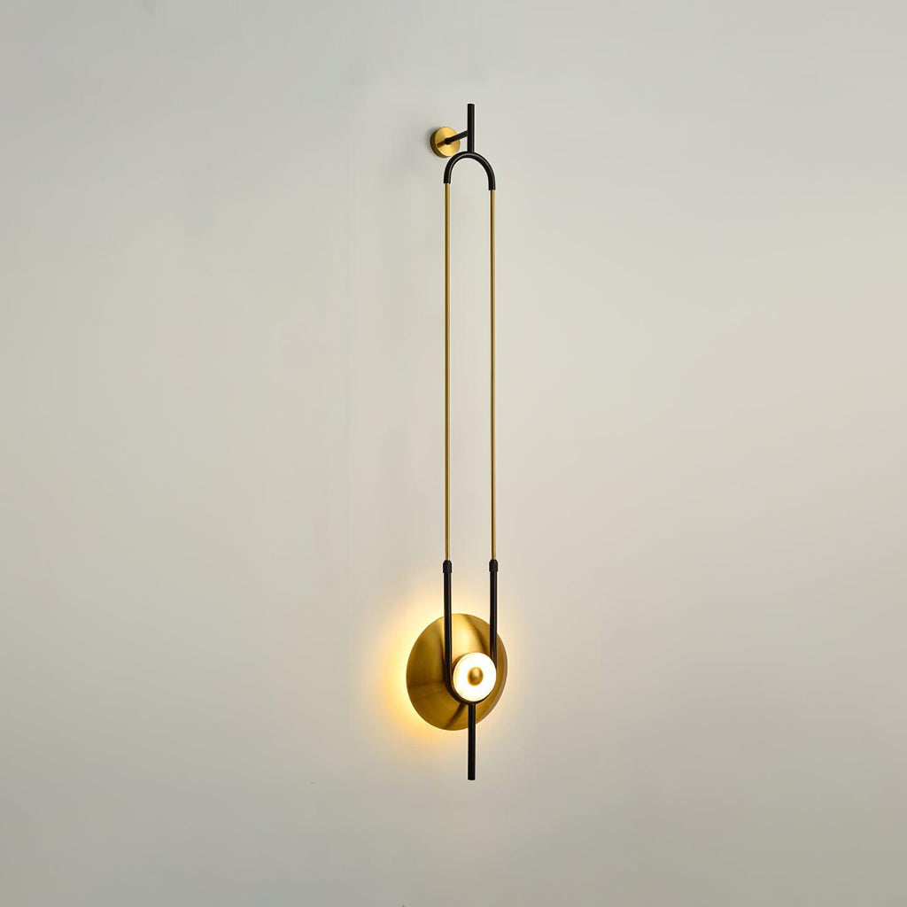 A single Clérachic wall sconce is shown on a plain white wall, its slim gold loop hanging from a small wall-mounted bracket.