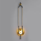 This Clérachic wall sconce is shown full length against a plain grey wall, from its wall bracket to the lit gold base.