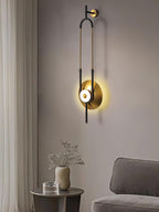 A Clérachic wall sconce glows beside a beige sofa and a side table topped with dried stems in a living room corner.