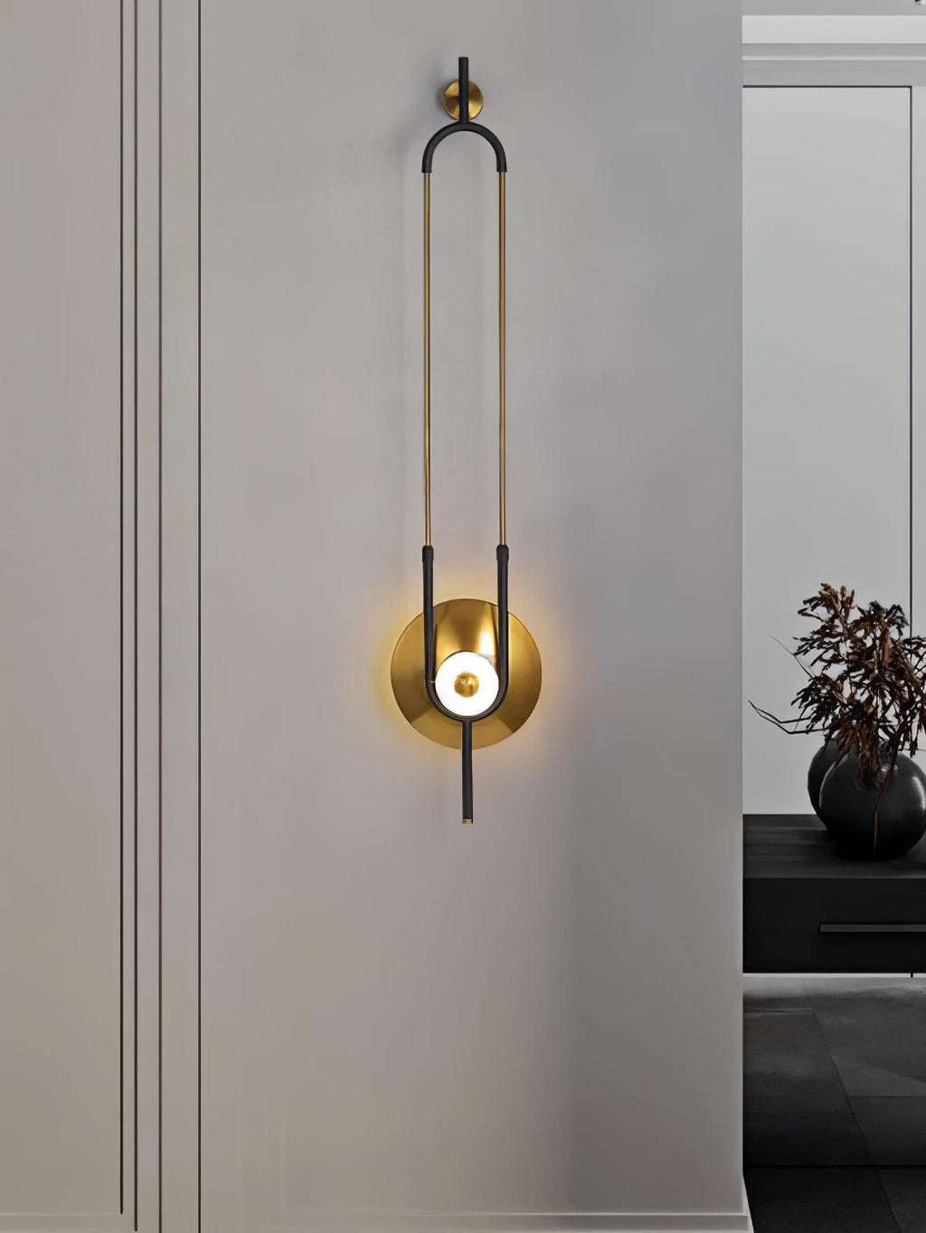 A Clérachic wall light glows beside a frosted glass panel, with a small dark vase visible in the background.