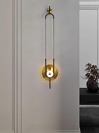 A Clérachic wall light glows beside a frosted glass panel, with a small dark vase visible in the background.