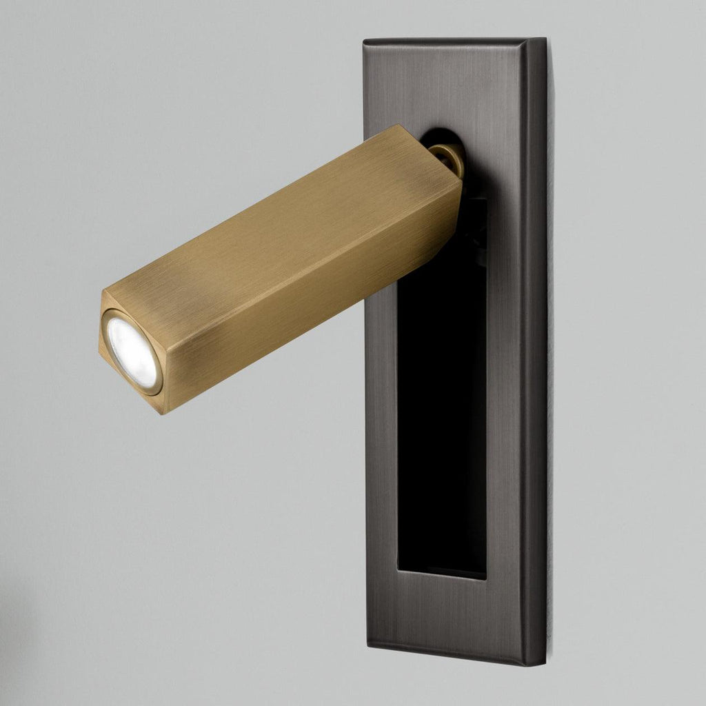 Folding bedside wall sconce angled to cast light over an open book