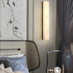Close crop of the black-framed Kristy lamp lit over a bedside table and upholstered headboard.