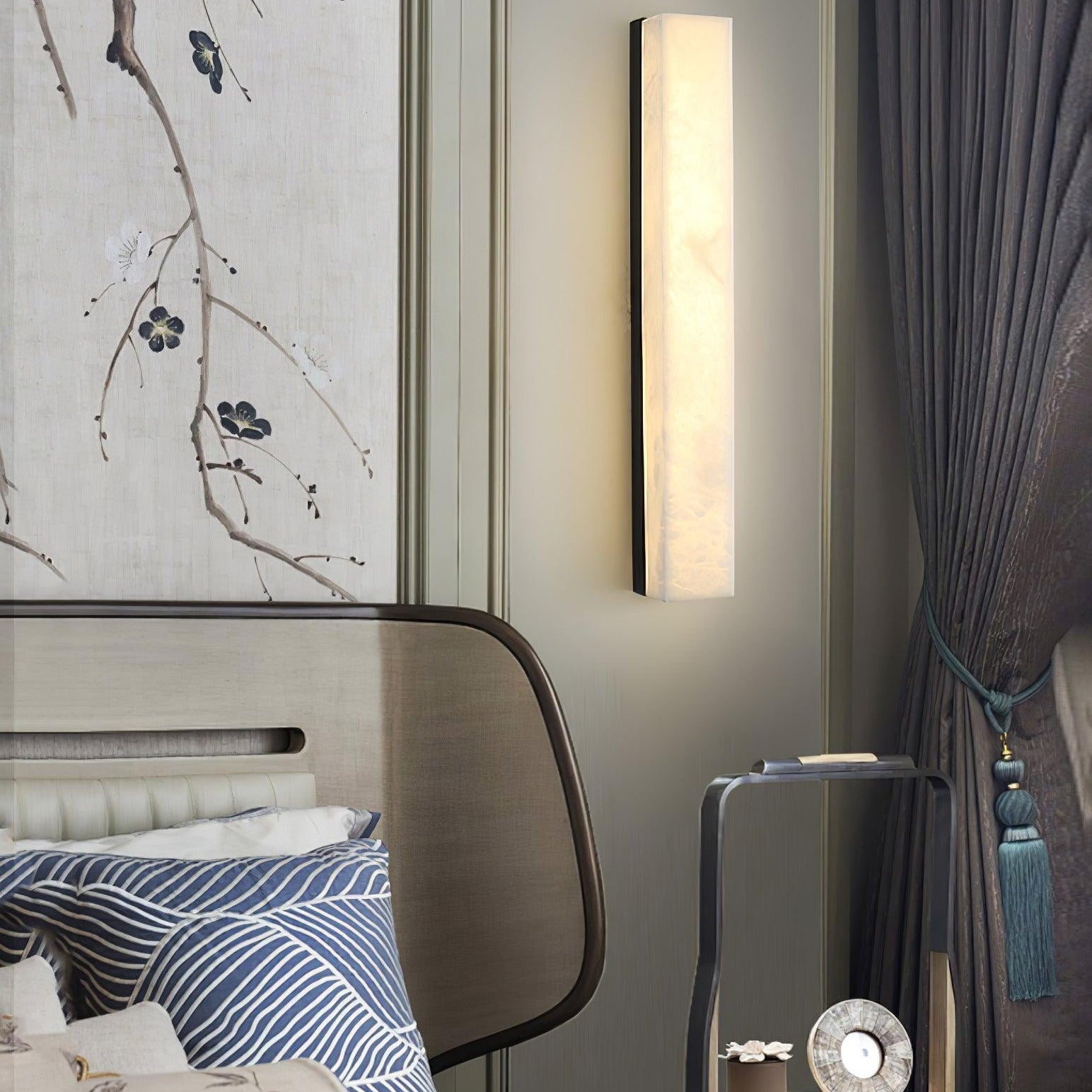 Close crop of the black-framed Kristy lamp lit over a bedside table and upholstered headboard.
