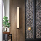 The same walnut entry wall with the Kristy lamp switched off, its pale stone face unlit.