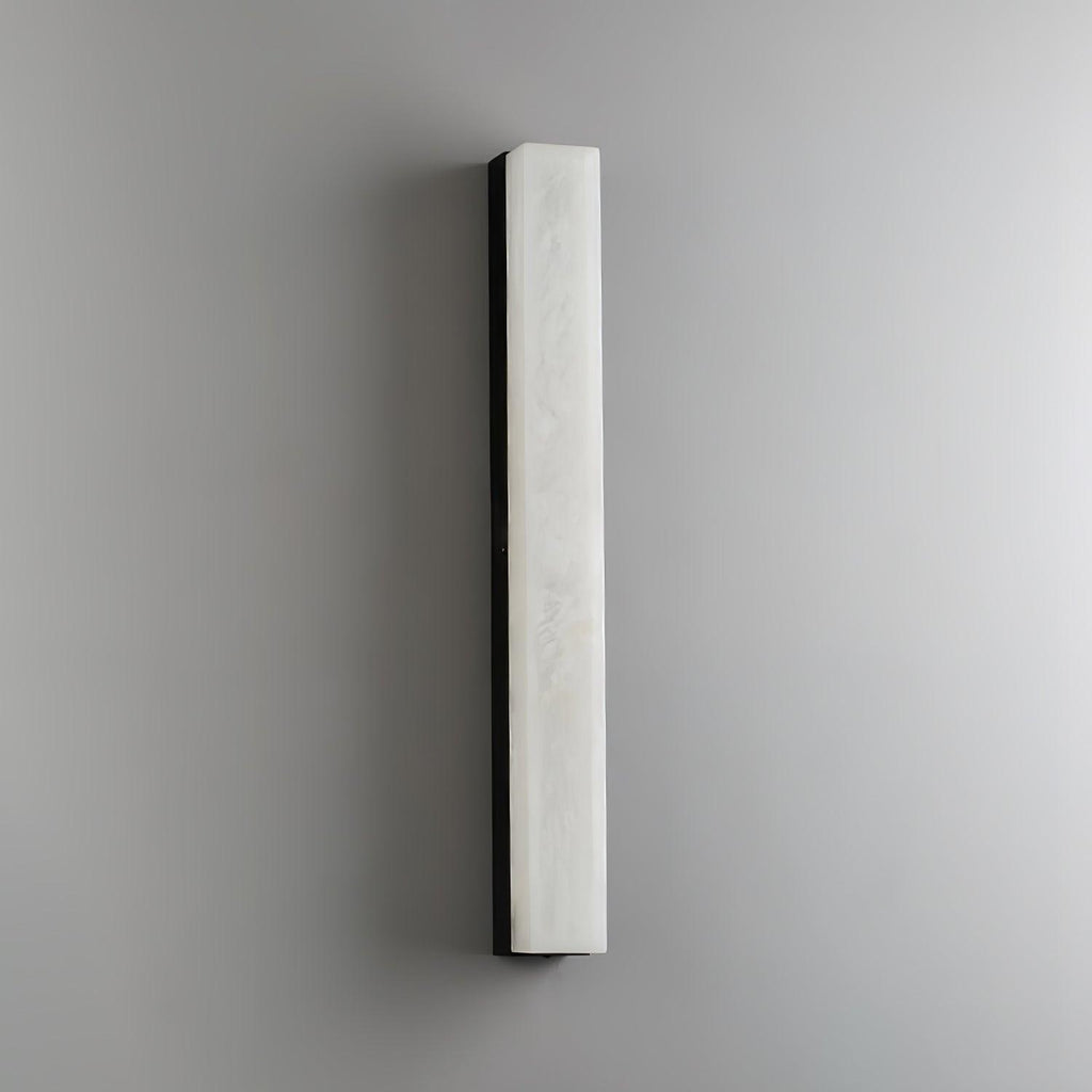 Unlit black-framed Kristy wall lamp on a grey wall, cool white stone face and dark edge.