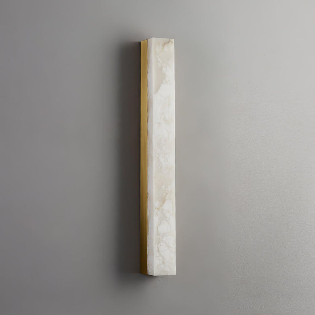 Unlit Kristy wall lamp on a grey wall, showing the brass frame and natural alabaster veining.