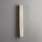 Unlit Kristy wall lamp on a grey wall, showing the brass frame and natural alabaster veining.