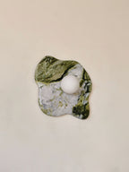 A tightly cropped view of this Clérachic wall light shows striped green marble meeting white stone within the same slab.