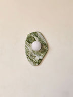 Shown in a narrow vertical crop, the diamond-cut marble of this Clérachic wall light stands unlit against a beige wall.