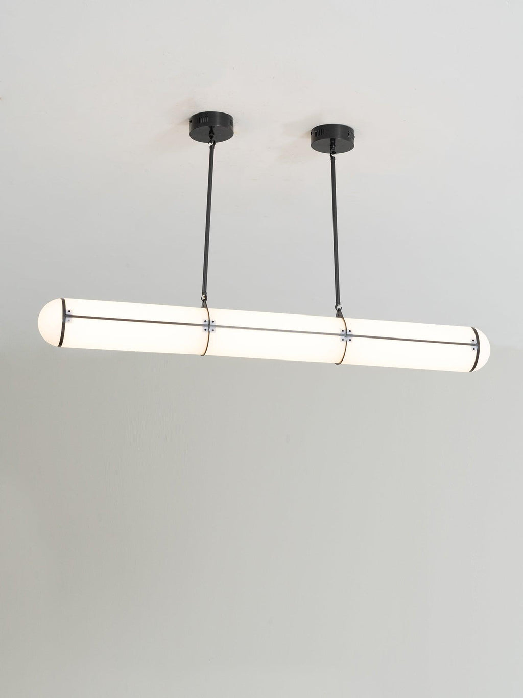 Linear cylindrical pendant light suspended over a dining table