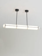 Linear cylindrical pendant light suspended over a dining table