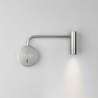 A sand nickel Clérachic wall sconce with a long arm casts light down a plain white wall.