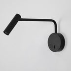 With its arm bent low, this black Clérachic wall sconce directs a warm beam down a grey backdrop.