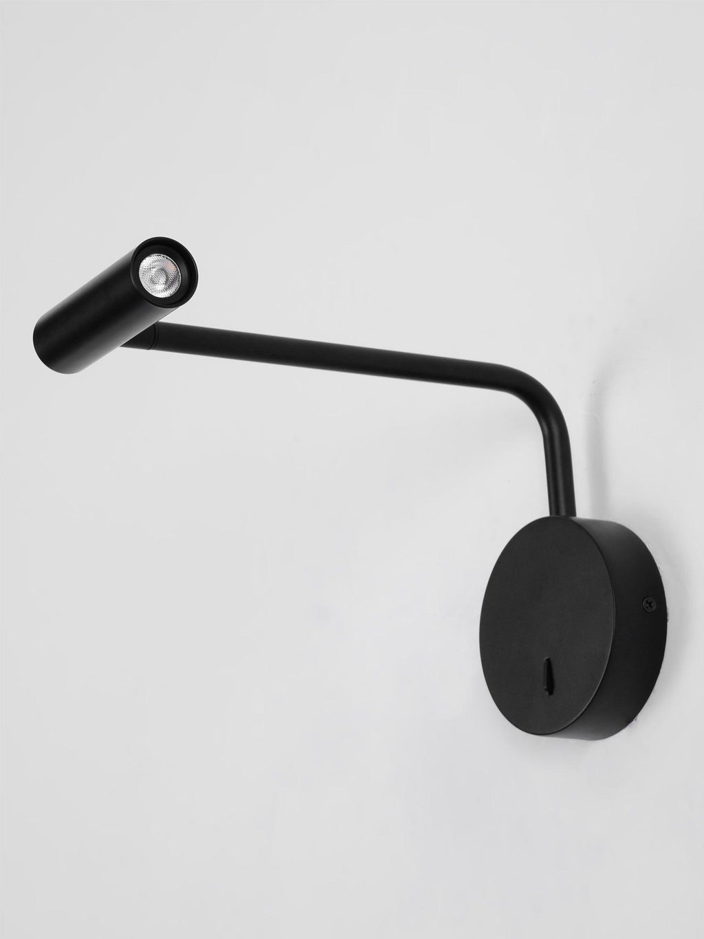 On a plain grey background, this black Clérachic wall sconce has its head angled forward.