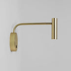 Unlit against a plain grey backdrop, this gold Clérachic wall sconce shows its long arm and disc base.