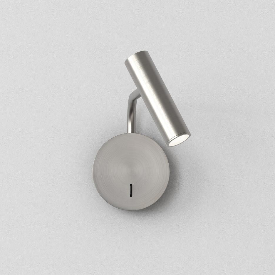 Its head tilted upward, this sand nickel Clérachic wall sconce is shown on a plain white backdrop.