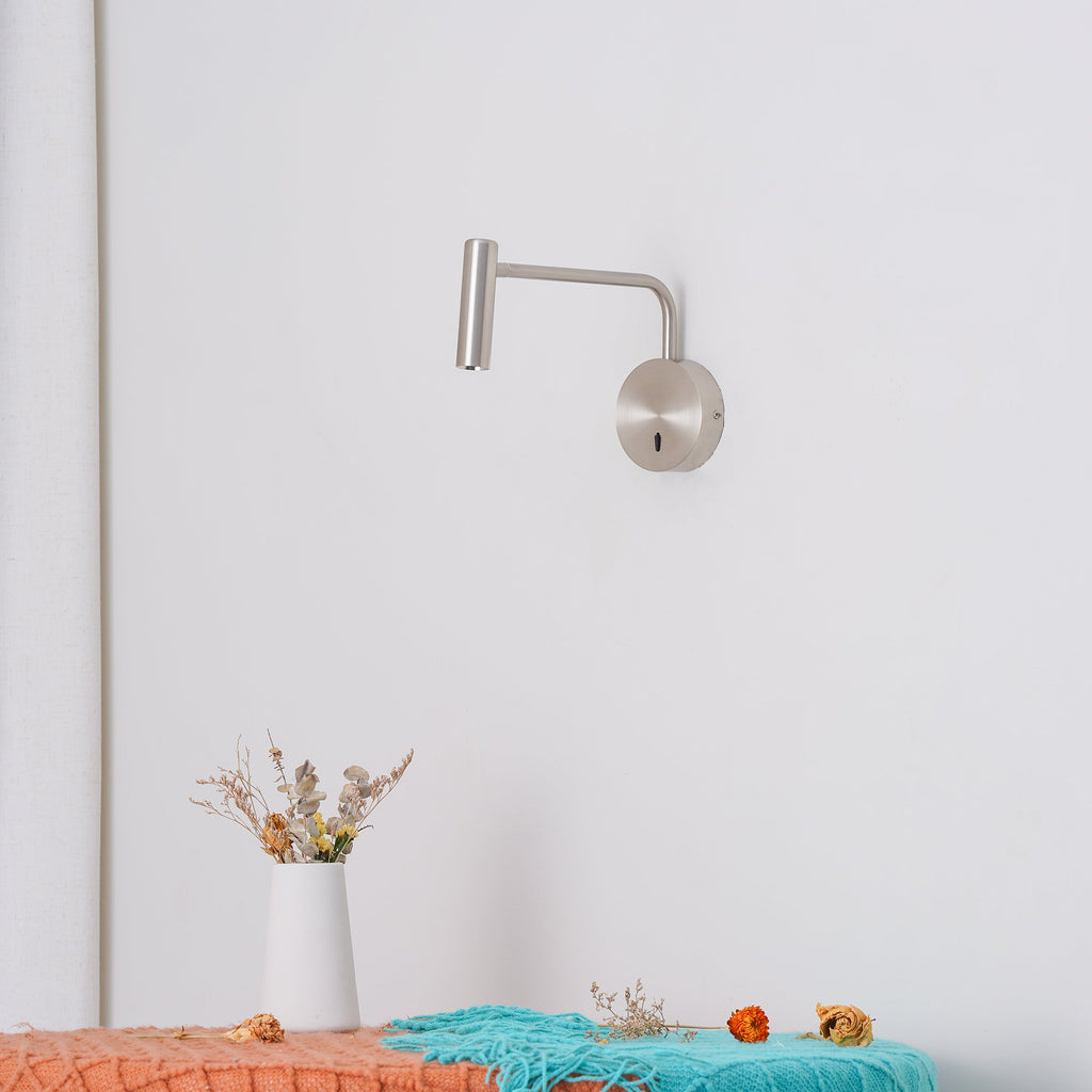 Above a bench styled with dried flowers, this sand nickel Clérachic wall sconce reaches out from the wall.