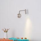 A sand nickel Clérachic wall sconce throws a warm beam down onto a bench styled with flowers.