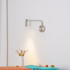 Above a bench with dried flowers and a teal throw, this sand nickel Clérachic wall sconce glows warmly.