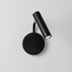 Photographed against a plain grey backdrop, this black Clérachic wall sconce has its head tilted for reading light.