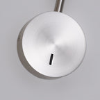 Close view of the brushed sand nickel disc base and switch on this Clérachic wall sconce.