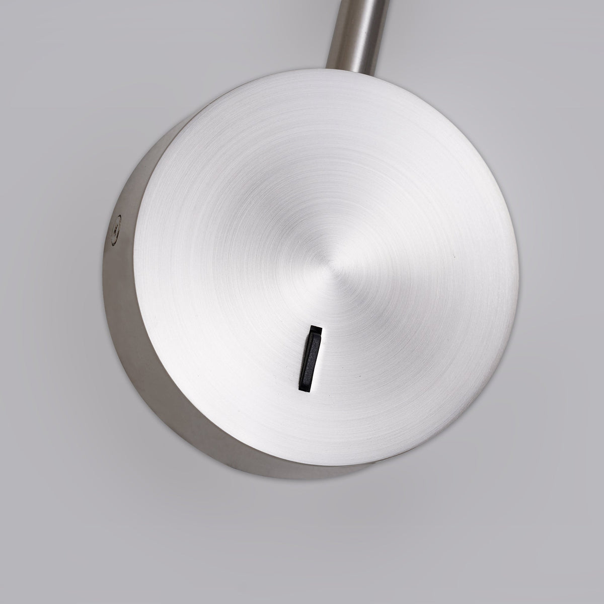 Close view of the brushed sand nickel disc base and switch on this Clérachic wall sconce.