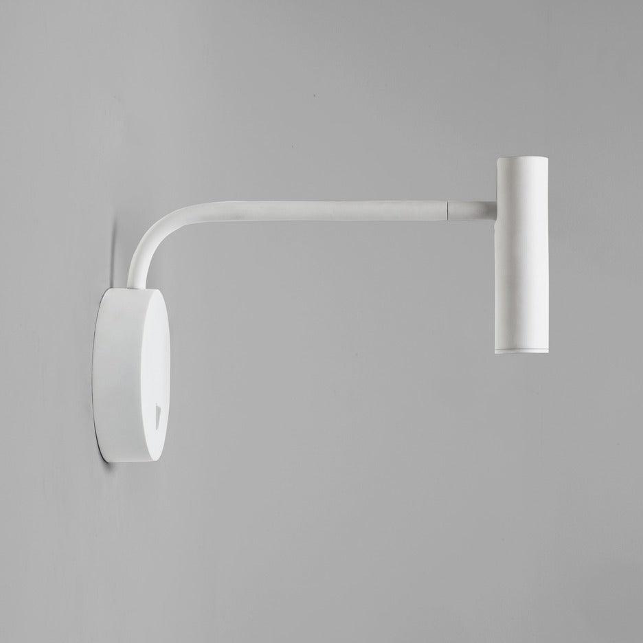 A white Clérachic wall sconce with a long bent arm, shown against a plain grey backdrop.