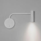 A white Clérachic wall sconce with a long arm casts light downward on a plain grey wall.