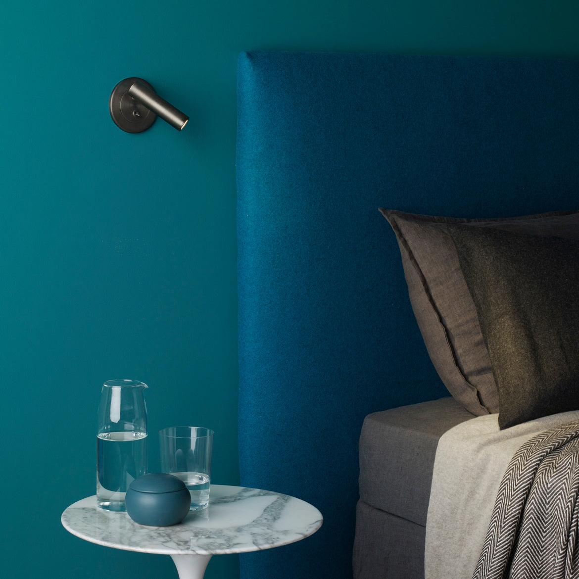 Pivoting wall sconce arm directing a focused reading beam
