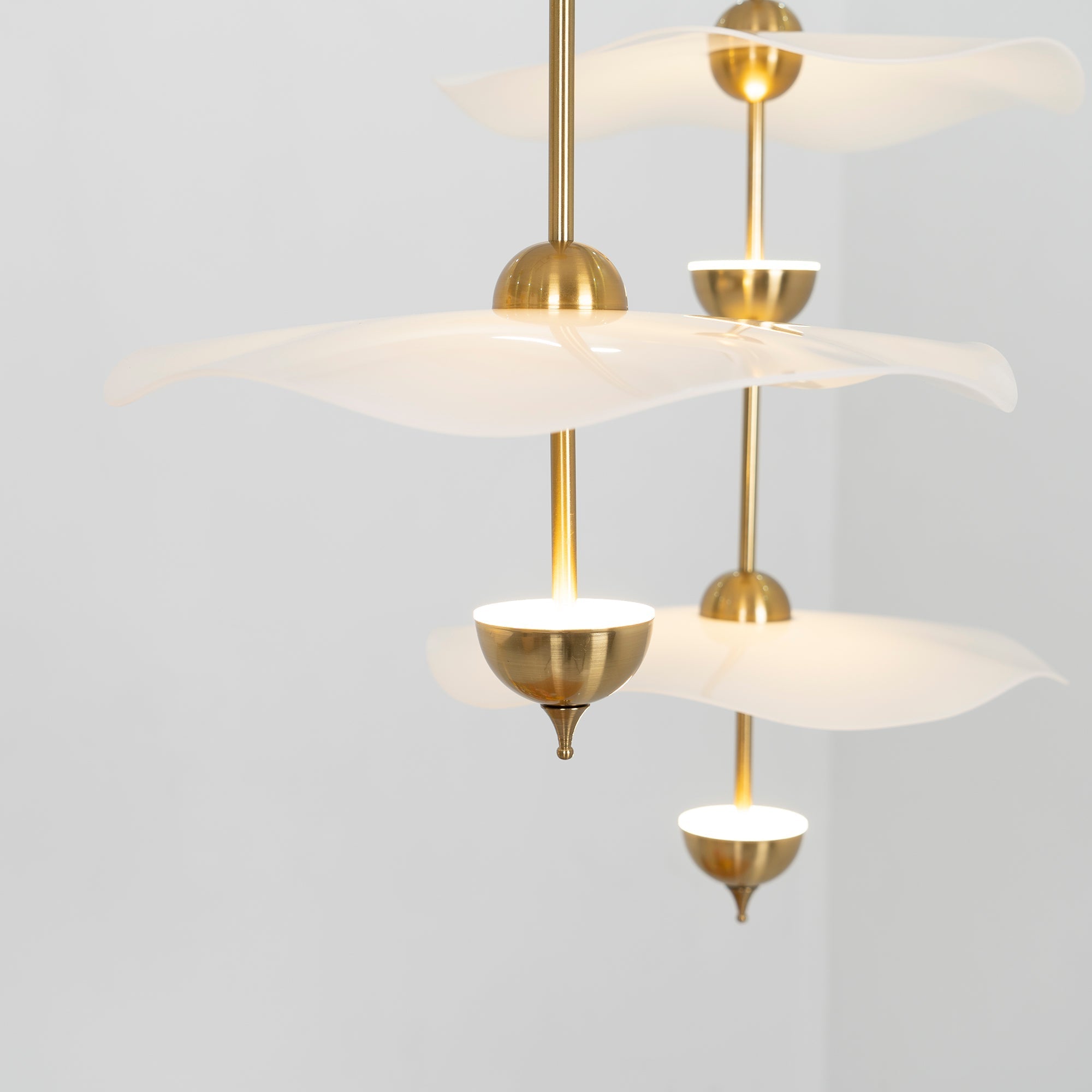 Envolee Double Biscuit gold and white pendant light glowing warmly over a living space