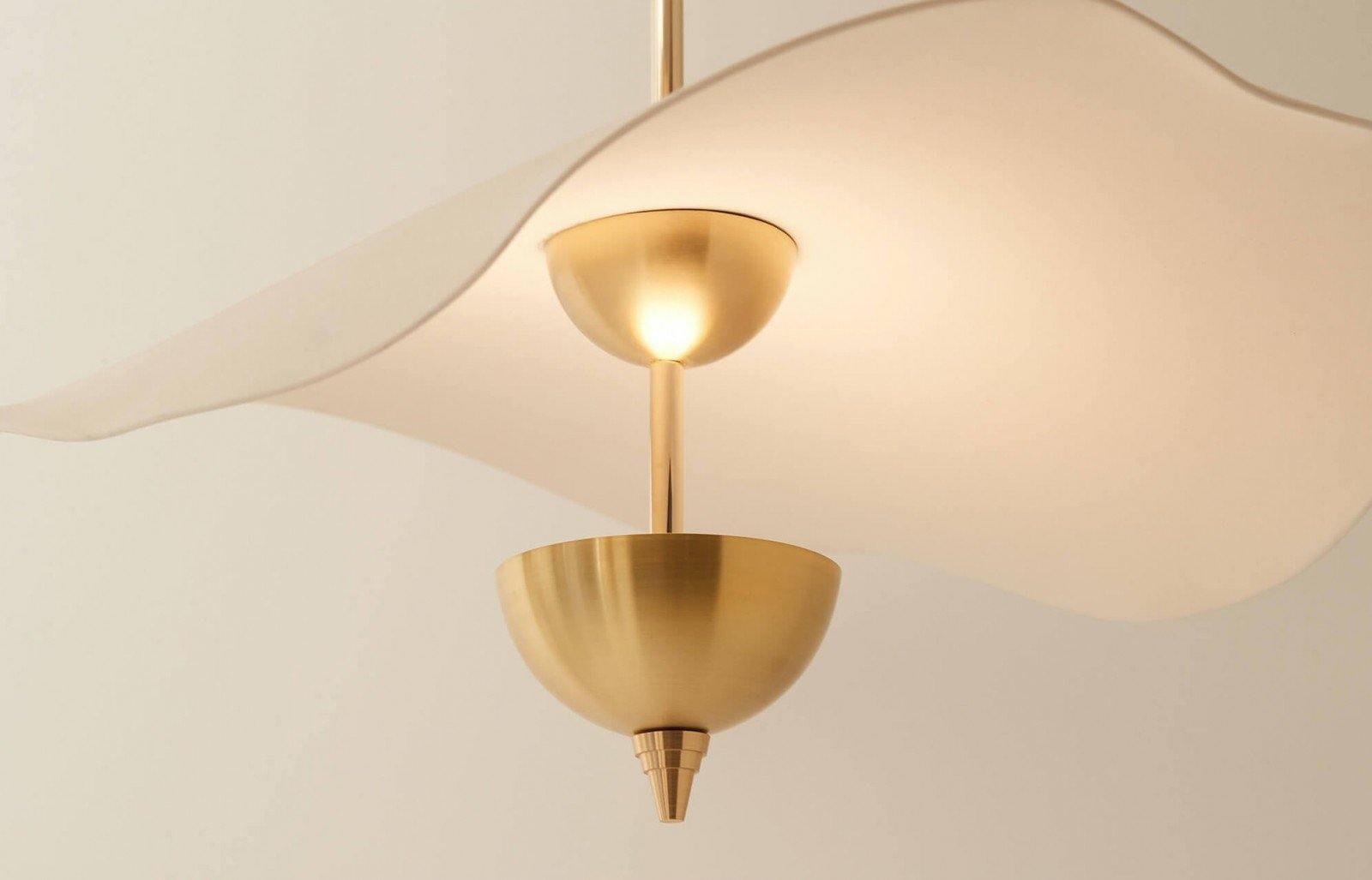 Envolee Double Biscuit gold and white pendant light glowing warmly over a living space