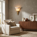 Beside a walnut credenza in a greige living room, this Clérachic sconce in brushed brass lights the wall above a cream armchair.