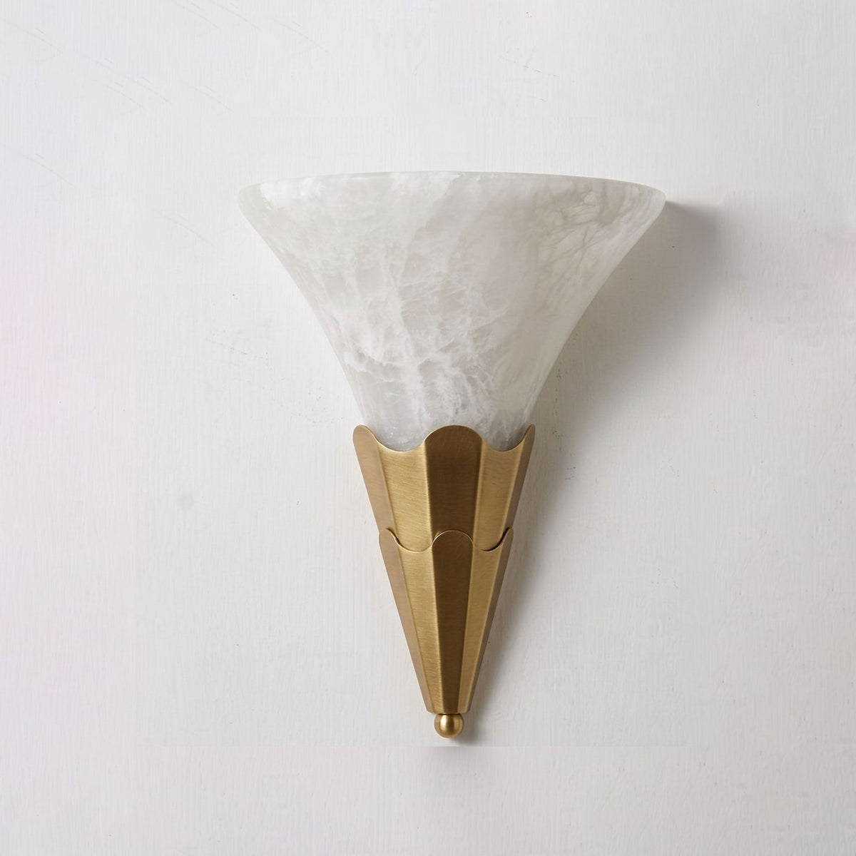 Lit against a plain white wall, this Clérachic sconce's alabaster shade glows above a brushed brass fluted base.