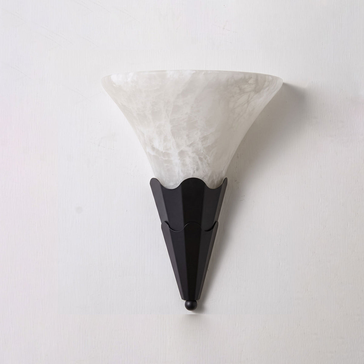 Against a plain white background, this Clérachic sconce's fan-shaped alabaster shade tops a matte black fluted base.