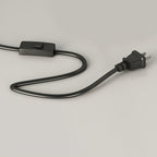 Detail of the Clérachic floor lamp's fabric-covered cord with its inline on/off switch and two-pin plug, laid on a plain grey background.