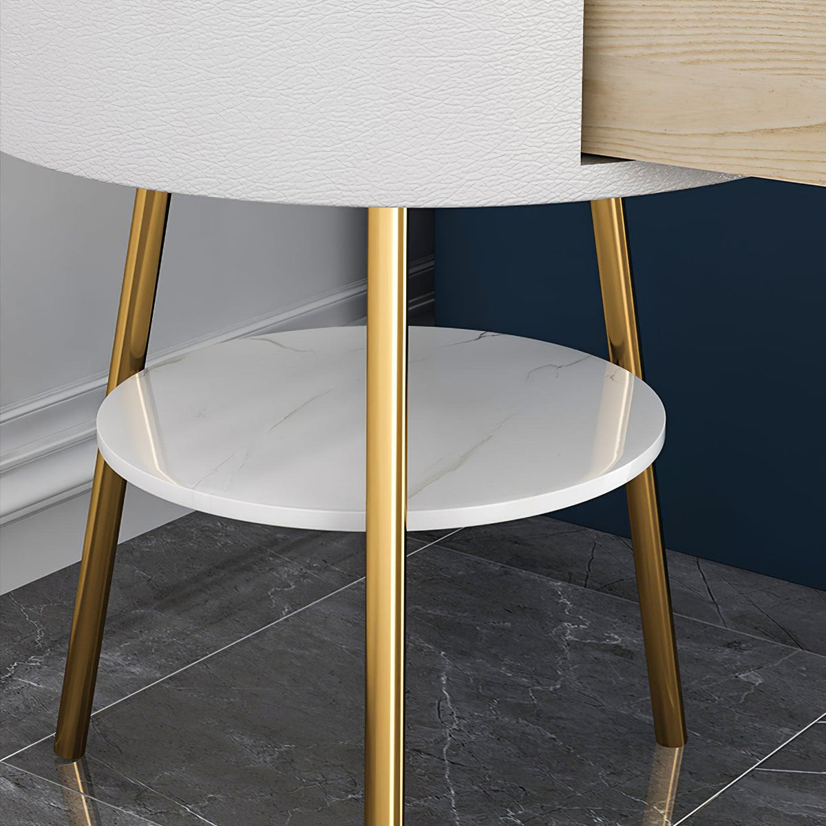 Close-up of the Clérachic side table's gold tripod legs and round white marble lower shelf, set beside a wood-panelled cabinet edge.