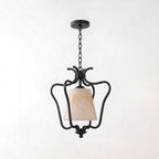 Set against a plain white background, the matte black finish of this Clérachic pendant scrolls into an open lantern frame.